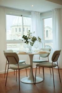 una mesa de comedor con sillas y un jarrón de flores en LC Apartaments Center, en Castellón de la Plana
