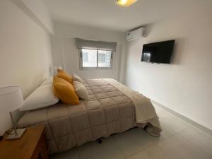 1 dormitorio con 1 cama con almohadas amarillas y TV en HAUS APARTAMENTOS en Salta