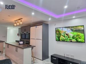 a kitchen with a tv hanging on the wall at Elegant Ensuite Rooms Near City Centre - Kunda House in Birmingham