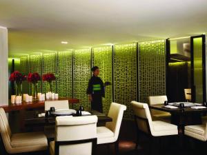 a person standing in a restaurant with tables and chairs at Hotel Gran Mahakam in Jakarta