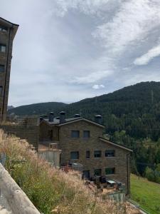 a large brick building on a hill with mountains in the background at FARIGOLA - 78PB Bordes d'Envalira in Bordes d´Envalira