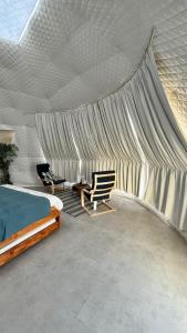 una camera da letto con tenda, letto e sedia di Starry Domes Desert Camp a Badīyah