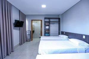 フォス・ド・イグアスにあるVila Nóbrega Residencialのベッド2台とテレビが備わるホテルルームです。