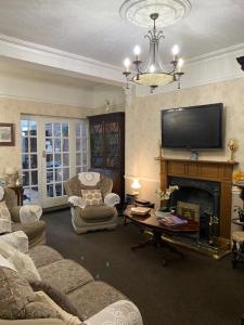 a living room with a fireplace and a tv at The Croft Guest House in Stratford-upon-Avon