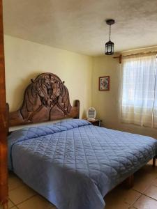 Schlafzimmer mit einem großen Bett mit einem Kopfteil aus Holz in der Unterkunft Casa de campo Mi muchachito in Pátzcuaro