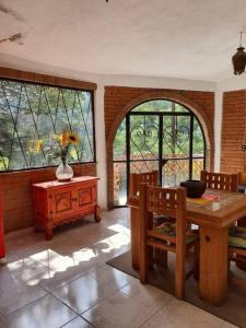 a dining room with a table and some windows at Casa de campo Mi muchachito in Pátzcuaro