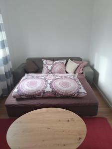 Una cama con almohadas rosas y blancas y una mesa de madera. en Ferienwohnung Brigitte en Goldkronach