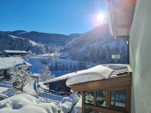 een met sneeuw bedekt huis met uitzicht op een berg bij Landler Auszeit in Thiersee