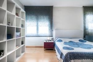 een slaapkamer met een bed en een boekenplank bij ¡Impactante apartamento a cero linea de mar! in Tarragona