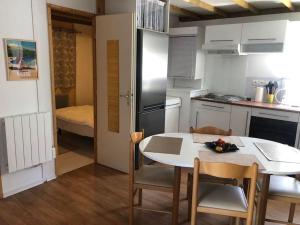 kuchnia ze stołem, krzesłami i lodówką w obiekcie Le 77 - chalet nature proche S.Besse w mieście Égliseneuve-dʼEntraigues