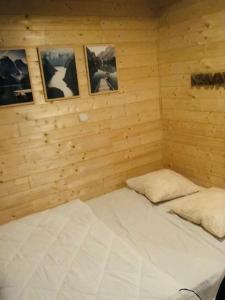 łóżko w drewnianym pokoju z obrazami na ścianie w obiekcie Le 77 - chalet nature proche S.Besse w mieście Égliseneuve-dʼEntraigues