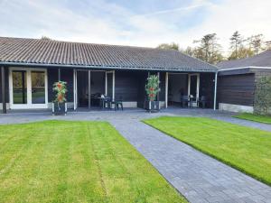 ein Haus mit einer Terrasse und einem Rasenhof in der Unterkunft Timmershoeve in Vorstenbosch