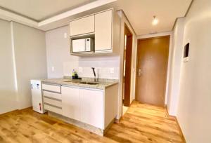 a kitchen with white cabinets and a wooden floor at Loft Executivo-Afonso Pena in Campo Grande