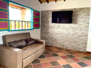 sala de estar con sofá y TV de pantalla plana en Hacienda El Encanto en Los Santos