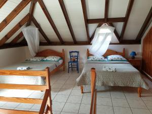 a bedroom with two beds and a chair at Chez Gisèle et Philippe duplex in Terre-de-Haut