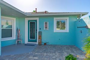 a blue house with a chair on a patio at Relaxing Beach Home with Fire Pit and Private Fenced Yard STEPS from the Sand! in New Smyrna Beach