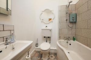 a bathroom with a toilet and a tub and a sink at Goilan Goch in Llandeilo