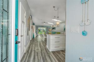 a kitchen with white cabinets and a hallway at Relaxing Beach Home with Fire Pit and Private Fenced Yard STEPS from the Sand! in New Smyrna Beach