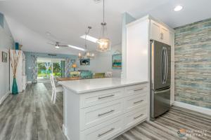 a kitchen with white cabinets and a refrigerator at Relaxing Beach Home with Fire Pit and Private Fenced Yard STEPS from the Sand! in New Smyrna Beach