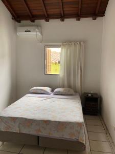 Schlafzimmer mit einem Bett und einem Fenster in der Unterkunft Suites Pouso Familiar José e Maria in Paraty