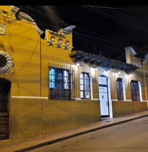 a yellow building with windows and a door at night at Hotel La Gran Casona in Tunja