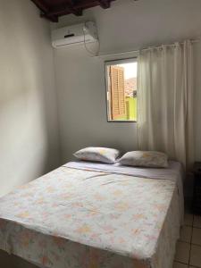 Bett in einem Zimmer mit Fenster und Tagesdecke in der Unterkunft Suites Pouso Familiar José e Maria in Paraty