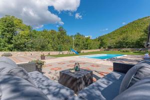 a patio with a table and chairs and a pool at Kuća za odmor ARIJA sa velikim vanjskim bazenom in Knin