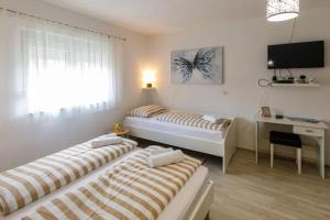 two beds in a room with a desk and a television at Kuća za odmor ARIJA sa velikim vanjskim bazenom in Knin