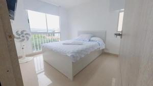 a white bedroom with a bed and a window at INCREIBLE APARTAMENTO Puerto Azul Club House RICAURTE in Ricaurte