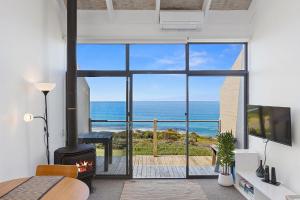 a living room with a fireplace and a view of the ocean at Whitecrest Eco Apartments Great Ocean Road in Apollo Bay