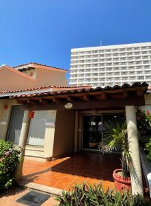 a house with a large building in the background at Villa 19 Con Playa 2 Recamaras dentro de Hotel en Ixtapa in Ixtapa