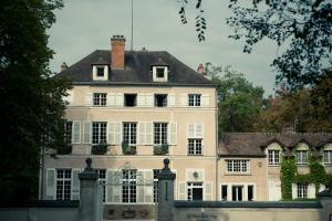 uma grande casa branca com uma bandeira em cima em Le Chateau De La Vierge em Bures-sur-Yvette