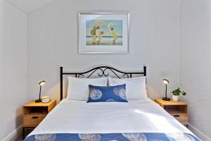 Whitecrest Eco Apartments Great Ocean Road في خليج أبولو: غرفة نوم مع سرير ووسائد زرقاء وبيضاء