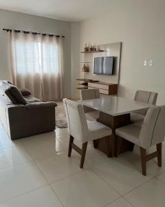 a living room with a table and chairs and a couch at Apto térreo Mãe Aparecida 8 pessoas 3km do santuário com WiFi ,ar condicionado nos quartos in Aparecida