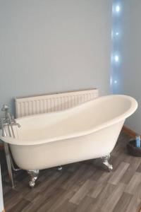 una vasca da bagno bianca seduta sopra un pavimento in legno di Ensuite Rooms a Wick
