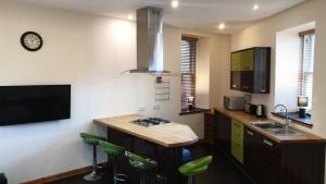a kitchen with a sink and a counter with green stools at Ensuite Rooms in Wick