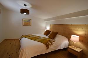 a bedroom with a white bed with a wooden headboard at VAUJANYLOCATIONS - L'Etendard in Vaujany