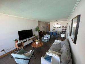 sala de estar con sofá, sillas y TV en apartamento con vista al mar y piscina., en Iquique