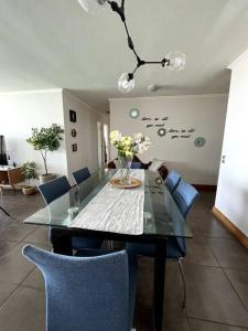 apartamento con vista al mar y piscina. في إكيكي: غرفة طعام مع طاولة زجاجية وكراسي زرقاء