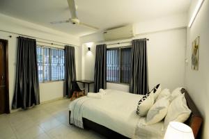 a bedroom with a white bed with black curtains at Gulshan Lovely 3-Bedroom Luxury Apartment in Dhaka