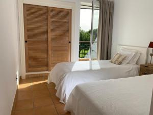 a bedroom with two beds and a window with a view at House of Rising Sun in Quarteira