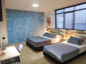 a bedroom with two beds and a table and a window at Neim Platinum Hotel in Medellín