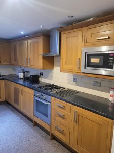 a kitchen with wooden cabinets and a blue stove top oven at No 5 Decent Homes ( Luxury Extra-large bedroom) in Ashton under Lyne