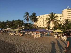 a beach with chairs and umbrellas and a building at Vacaciones Playa Club Casa Blanca Same Esmeraldas in Same