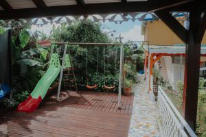 einen Spielplatz mit Rutsche auf dem Deck in der Unterkunft Résidence Le Palmier Royal in Sainte-Rose