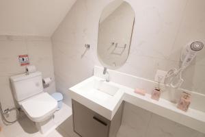 un bagno bianco con lavandino e specchio di Pé na Vila a Porto De Galinhas Altre 39 foto