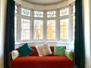 a living room with a red couch in front of windows at 3 Bedroom Spacious Seaside Apartment with Estuary Views in Southend-on-Sea