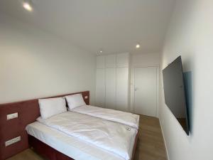 una piccola camera da letto con un letto con lenzuola bianche di MIZU Apartamenty - Westin a Kołobrzeg