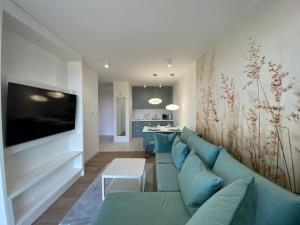 un soggiorno con divano blu e TV di MIZU Apartamenty - Westin a Kołobrzeg