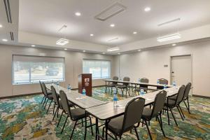 Best Western Plus Executive Residency Antioch Inn في أنتيوك: قاعة اجتماعات مع طاولات وكراسي وشاشة عرض